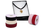 Jewelry set with a necklace and three spools of ribbon on a white background